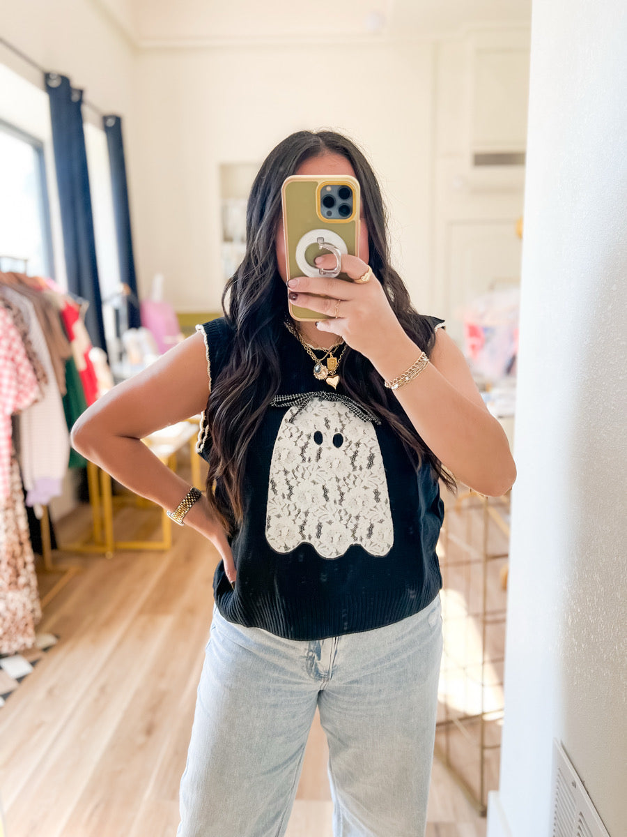 Person wearing a black t-shirt with a white ghost design in a room.