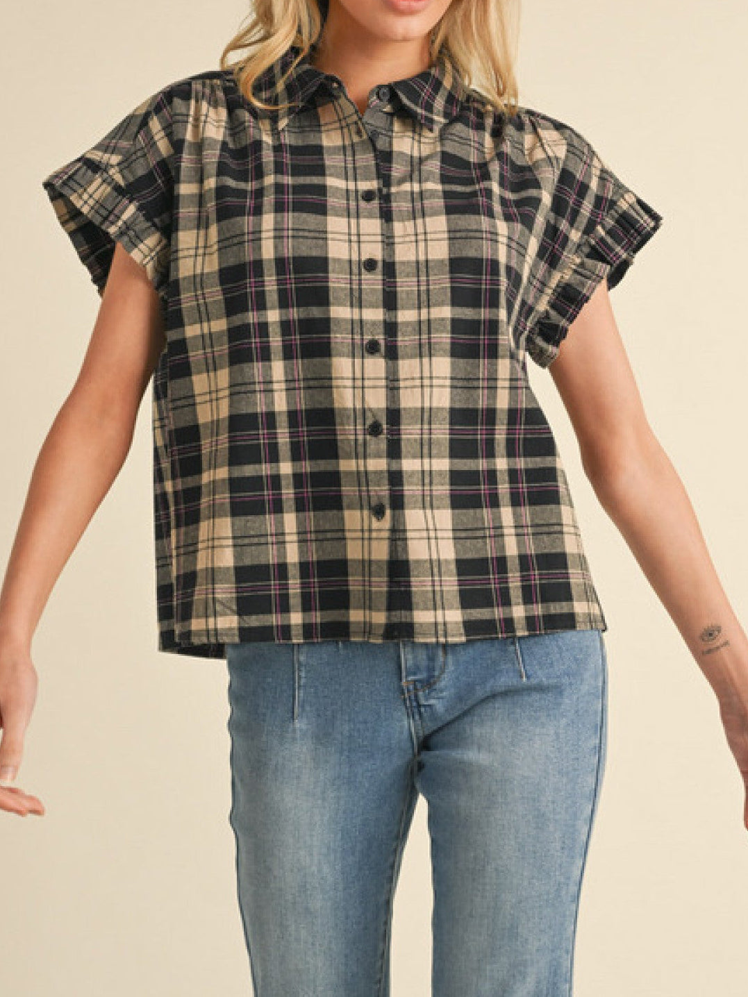 Woman wearing a plaid shirt and jeans on a beige background
