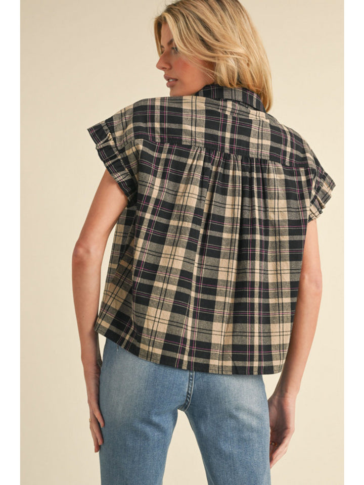 Woman wearing a plaid shirt and jeans against a beige background