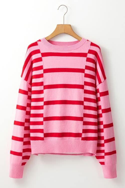 Pink and red striped sweater on a wooden hanger against a white background