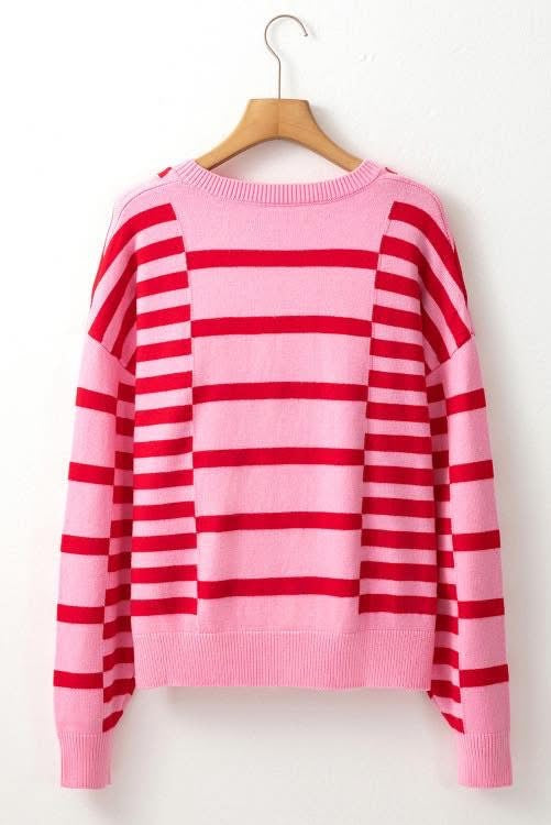 Pink and red striped sweater on a wooden hanger against a white background
