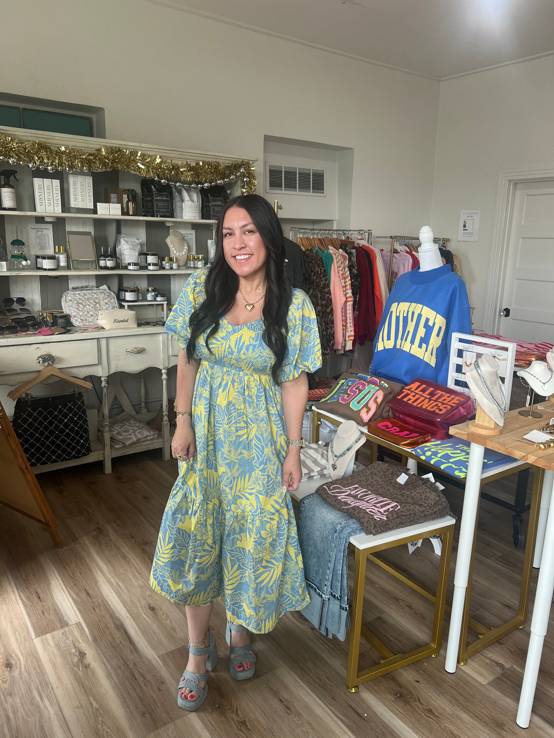 Woman in a yellow and blue cotton smocked floral midi dress standing in boutique 