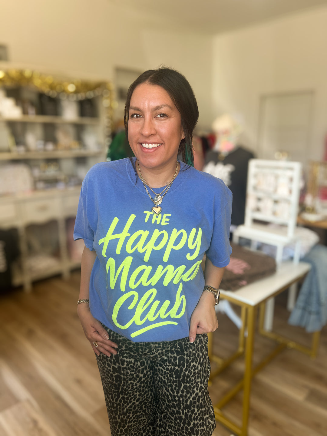 Woman wearing blue tshirt with “the happy mama club” written in neon 