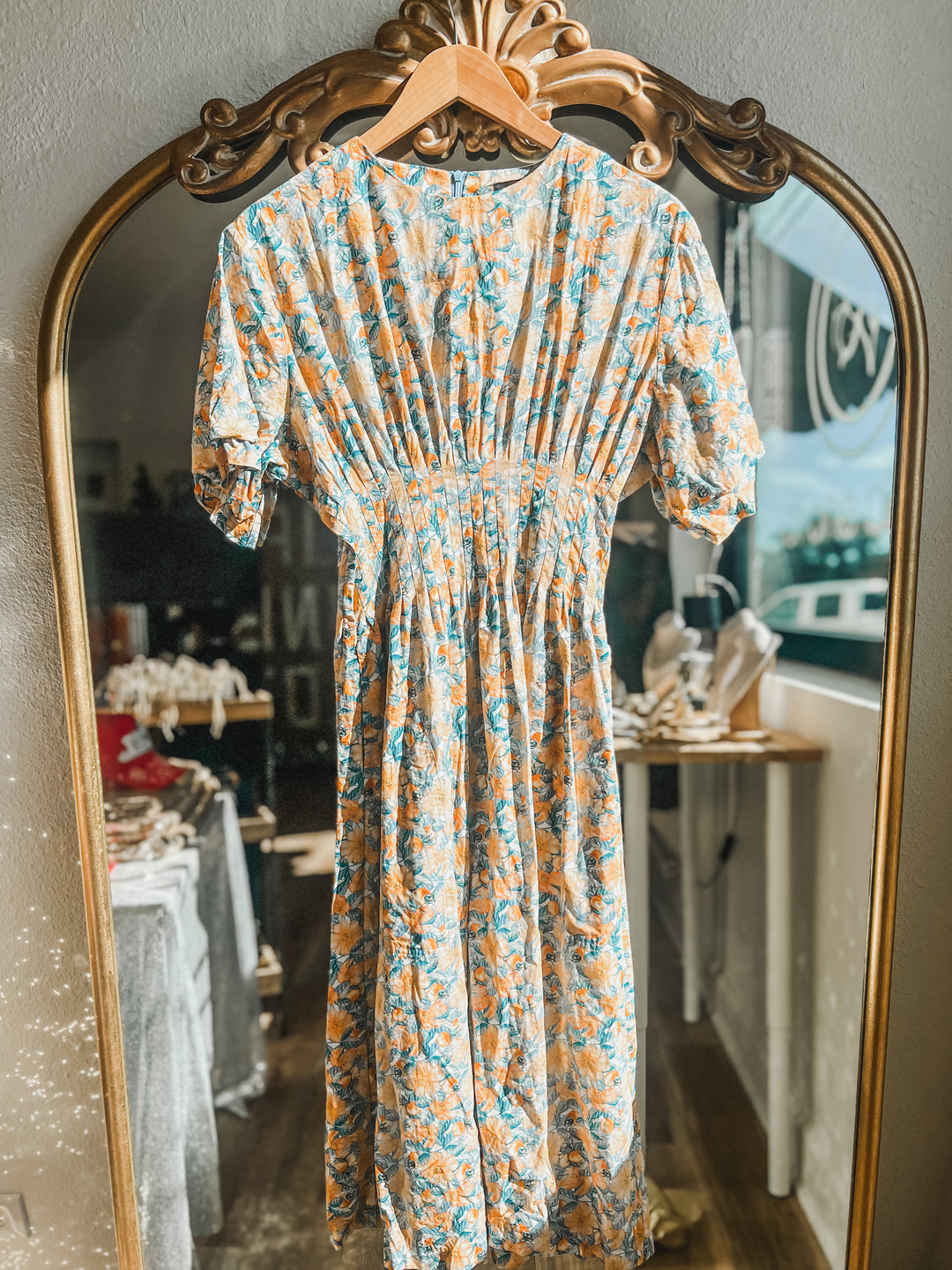 Floral dress hanging on a mirror with a store interior reflection