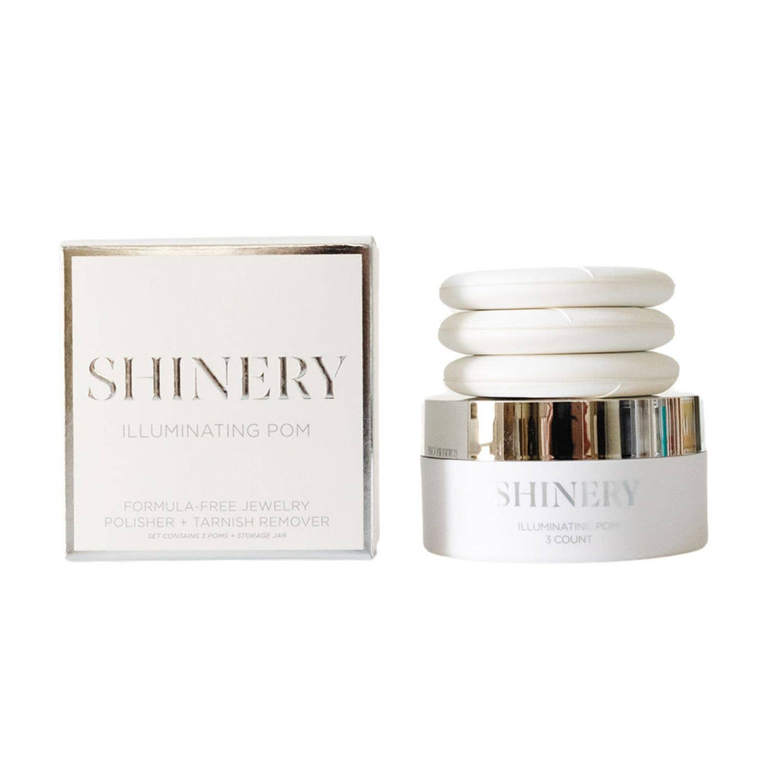 The image shows a jewelry polisher named 'SHINERY Illuminating Pom Tarnish Eraser'. It includes a white box packaging with the product visible through a clear window.