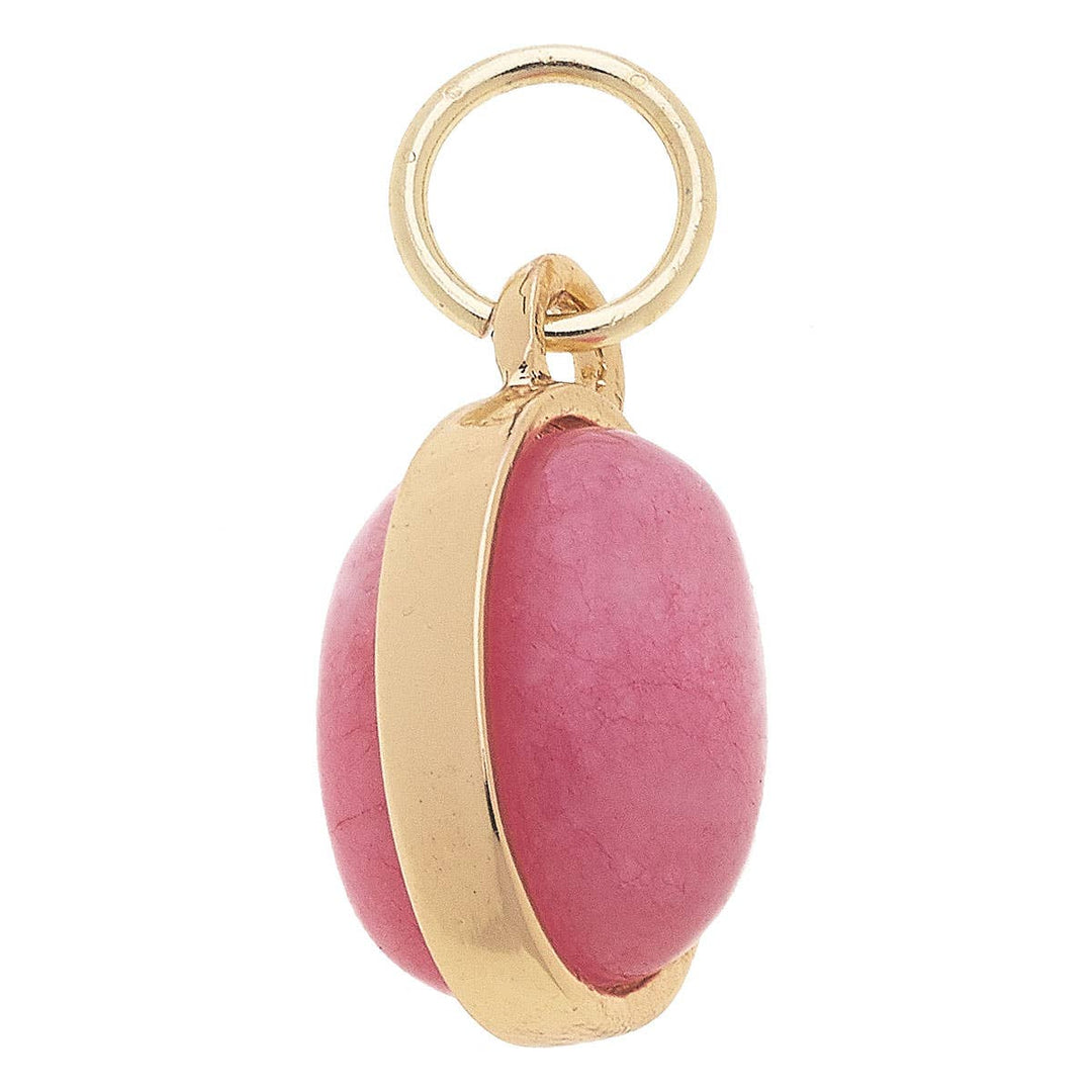 A gold-plated charm with a light pink dyed jade gemstone.