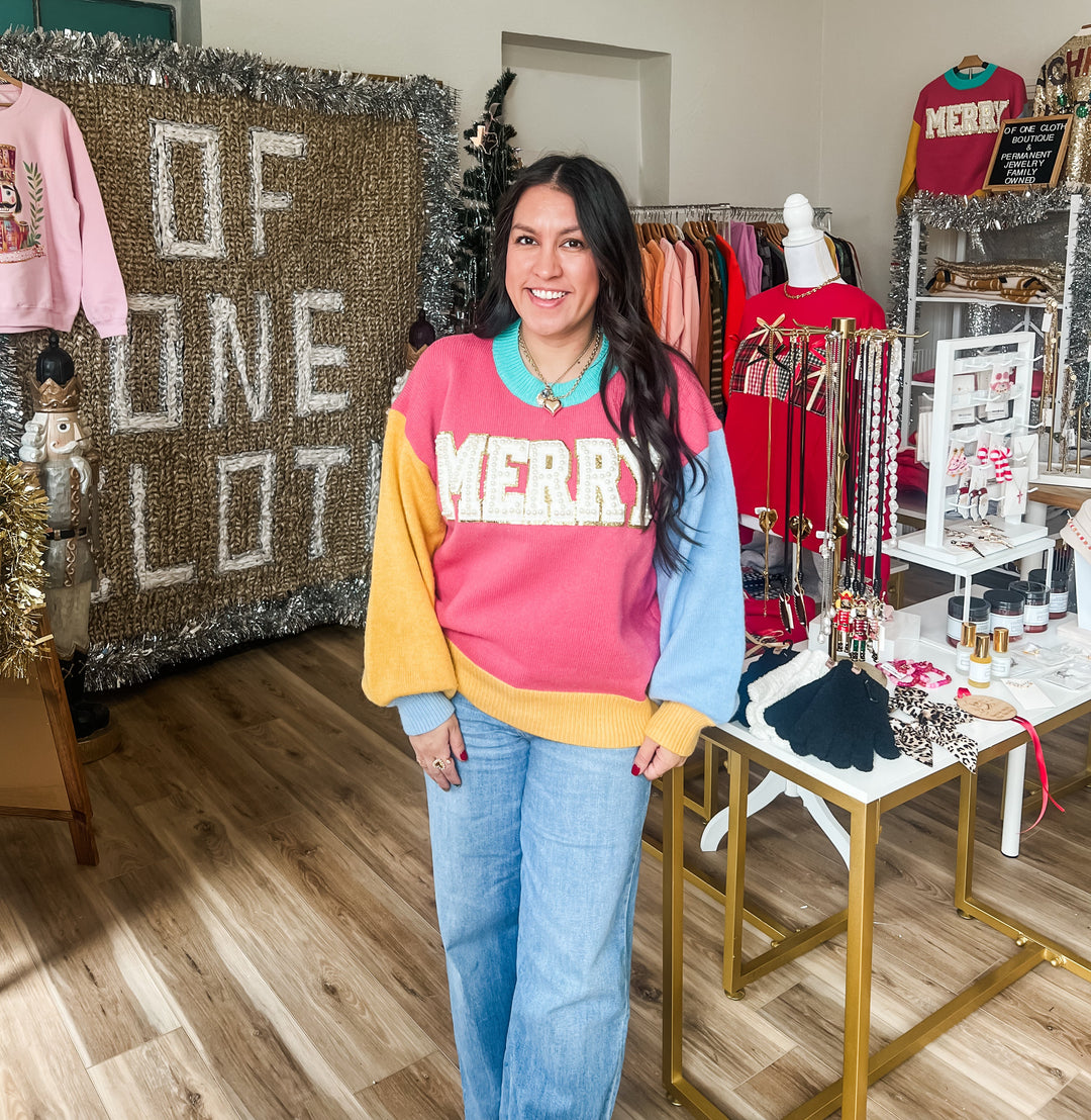 woman wearing a colorful sweater with "MERRY" and pearl accents