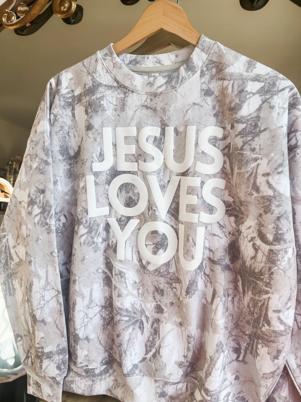 Camoflauge cream sweatshirt with "Jesus Loves You" text