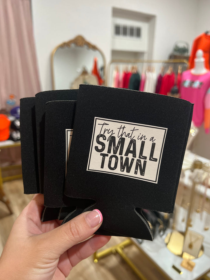 Two black koozies with white text holding a beverage, one koozie shows the front side with the text &