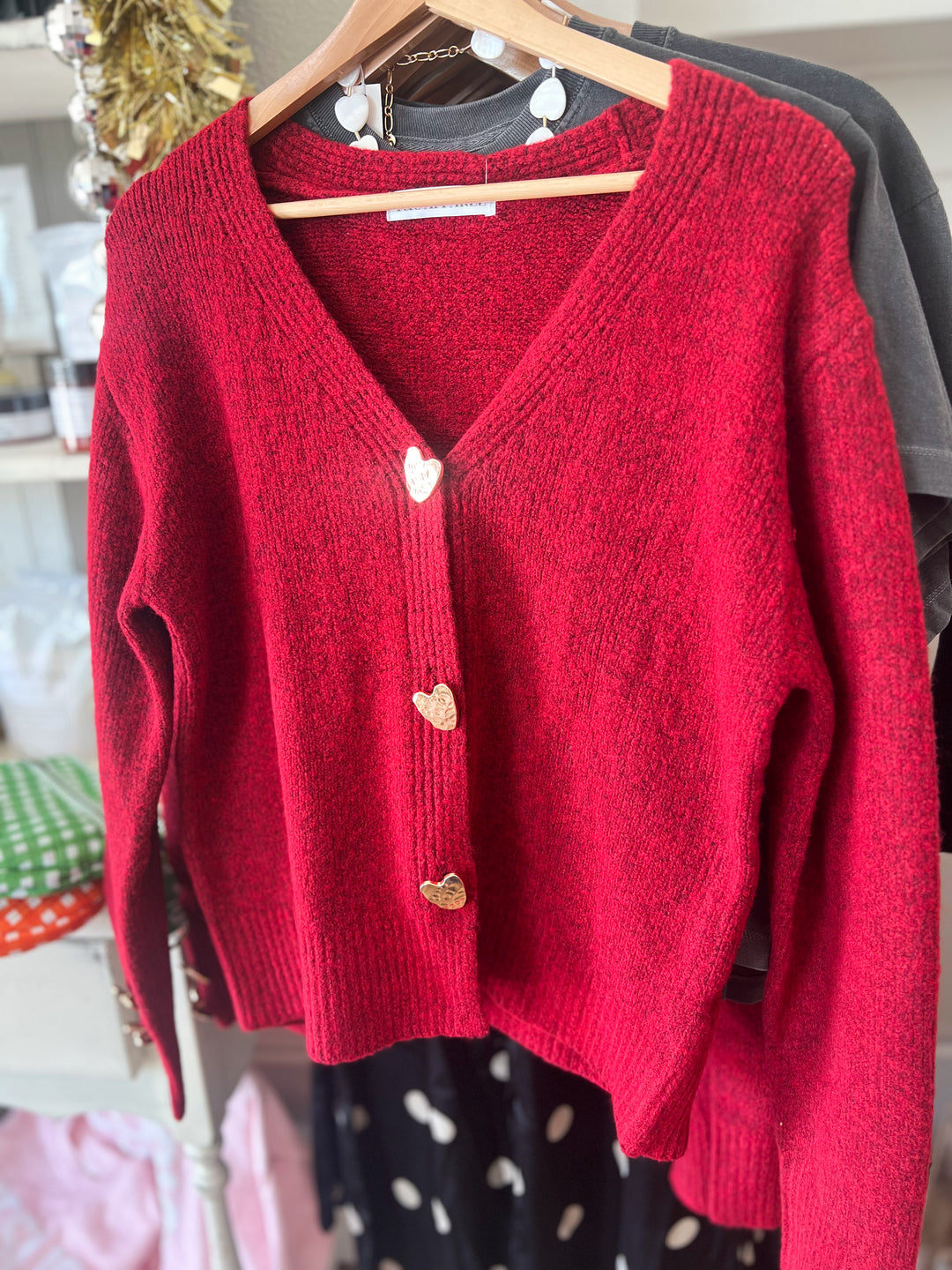 Red cardigan with heart-shaped buttons on a hanger