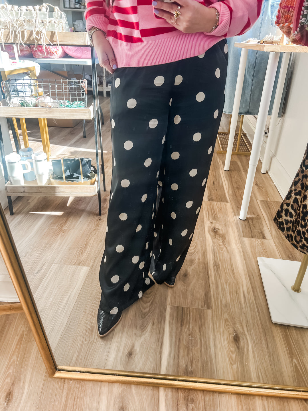 Woman wearing black pants with white polka dots and a pink sweater
