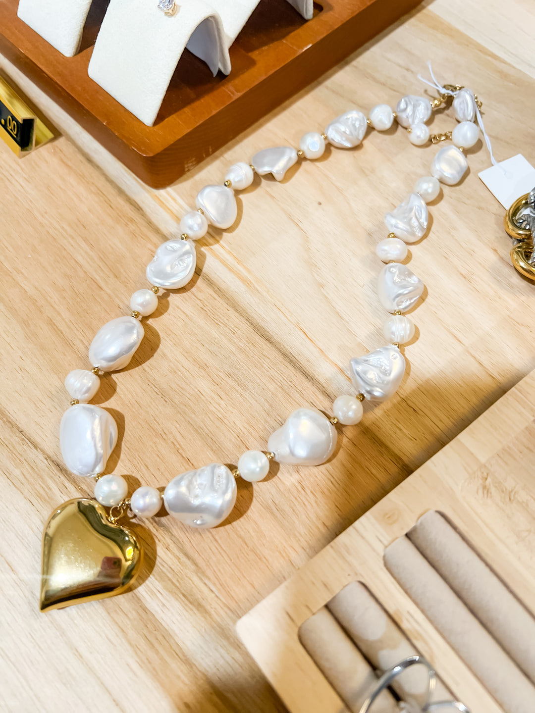 Pearl necklace with a gold heart pendant on a wooden surface