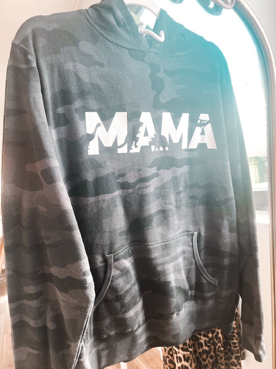 Camouflage hoodie with 'MAMA' text on a hanger