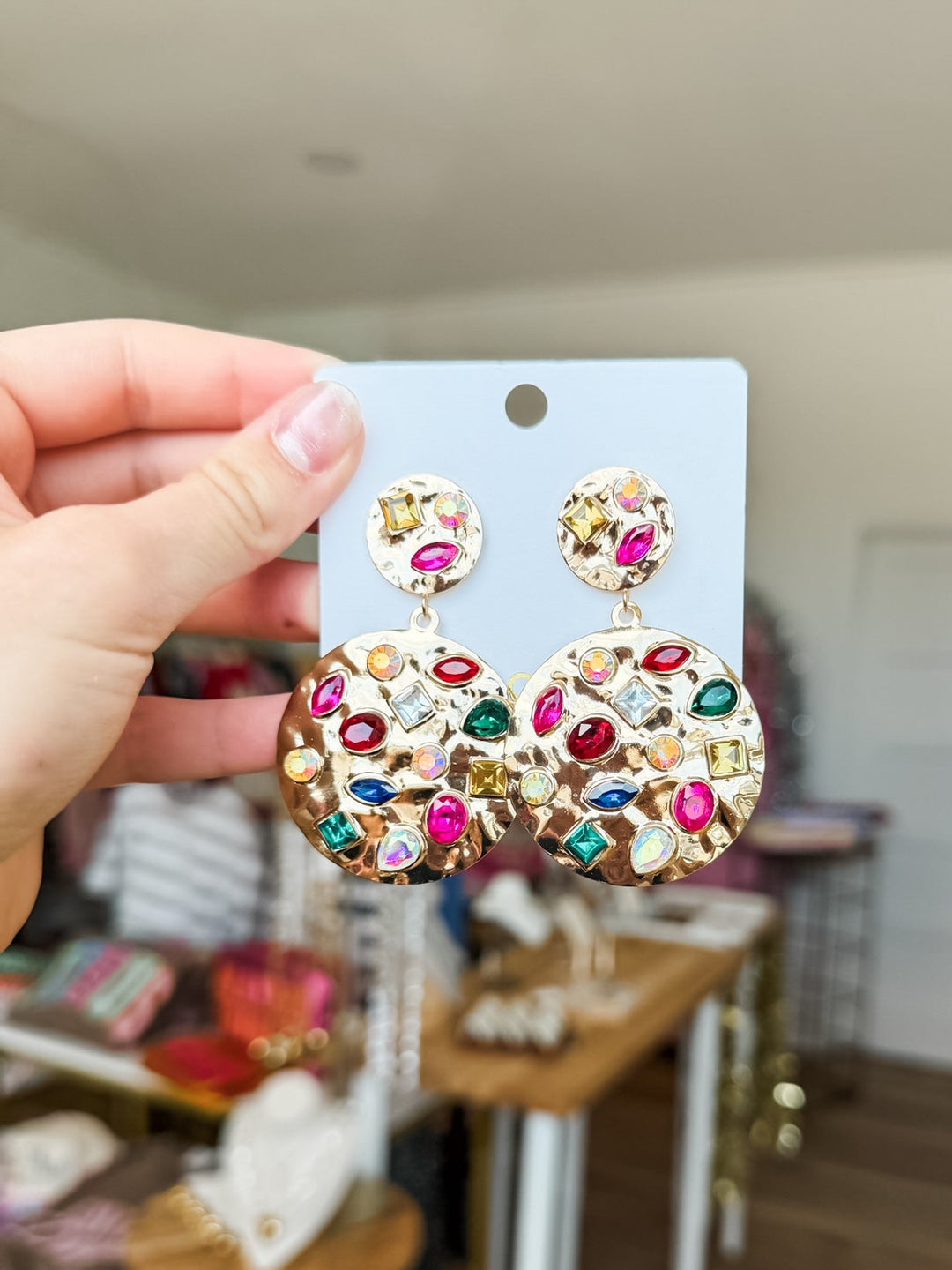 Gold hammered jewel earrings on a display card in boutique