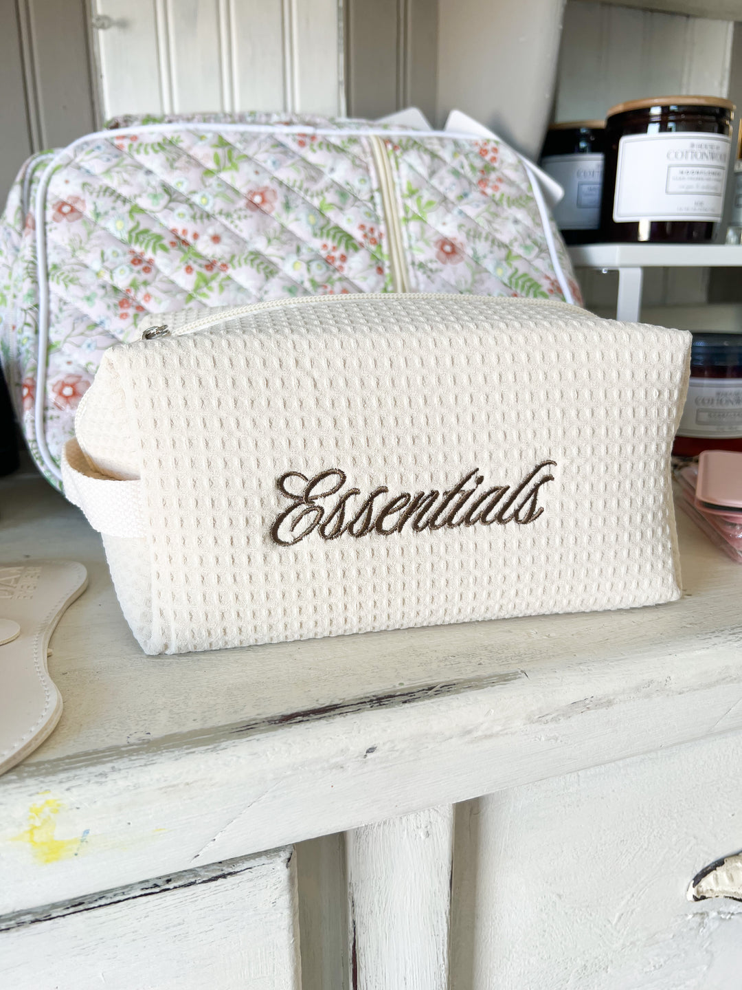 White toiletry bag with 'Essentials' text on a wooden surface