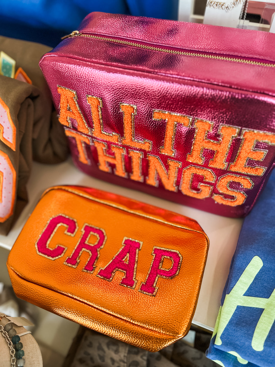 Two pouches with text on them, one pink and one orange, displayed against a blurred background.