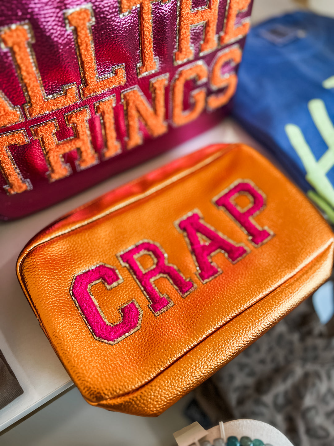 Orange pouch with pink text 'CRAP' on a blurred background