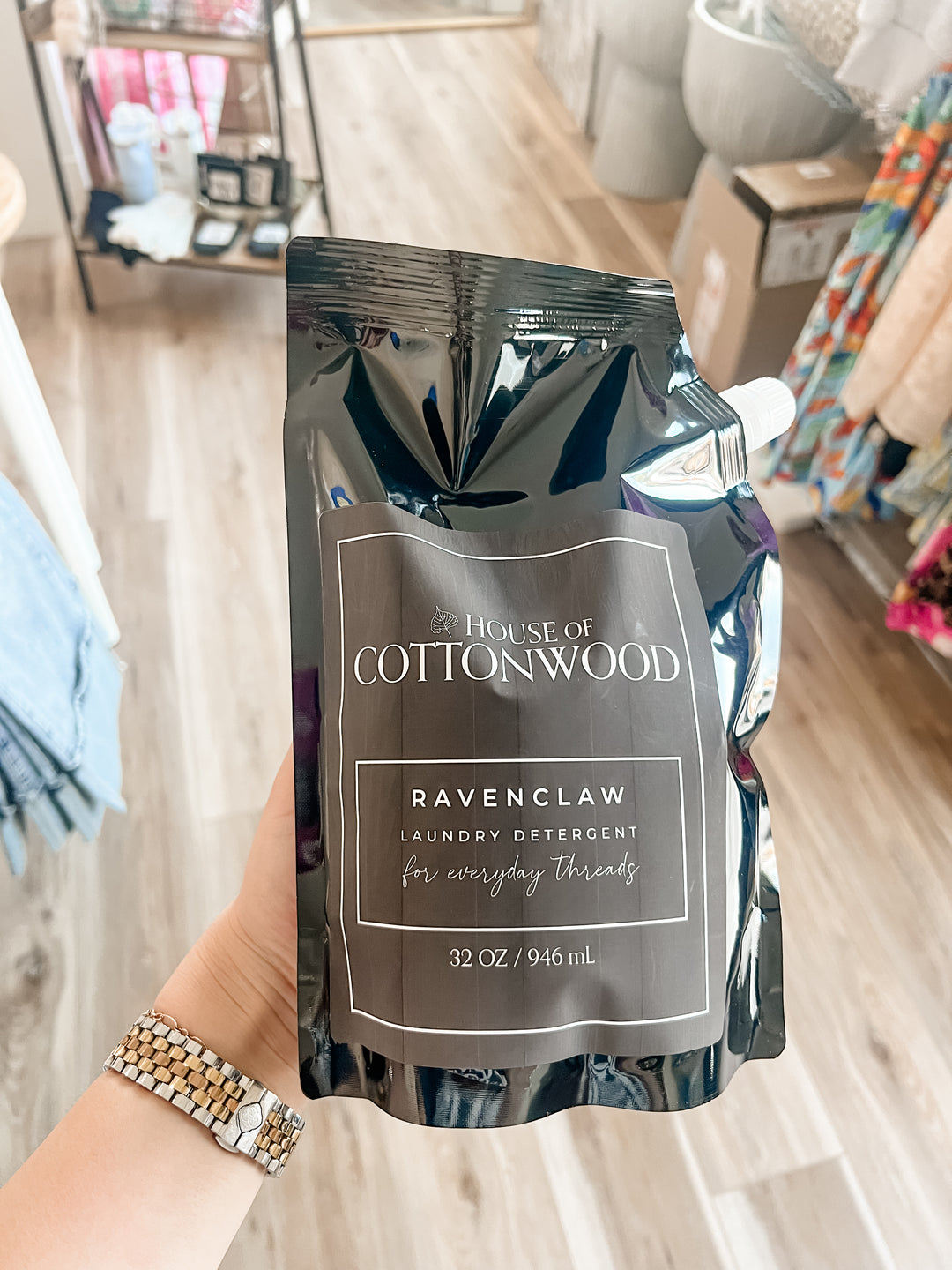 House of Cottonwood Ravenclaw laundry detergent packaging held by a person indoors.
