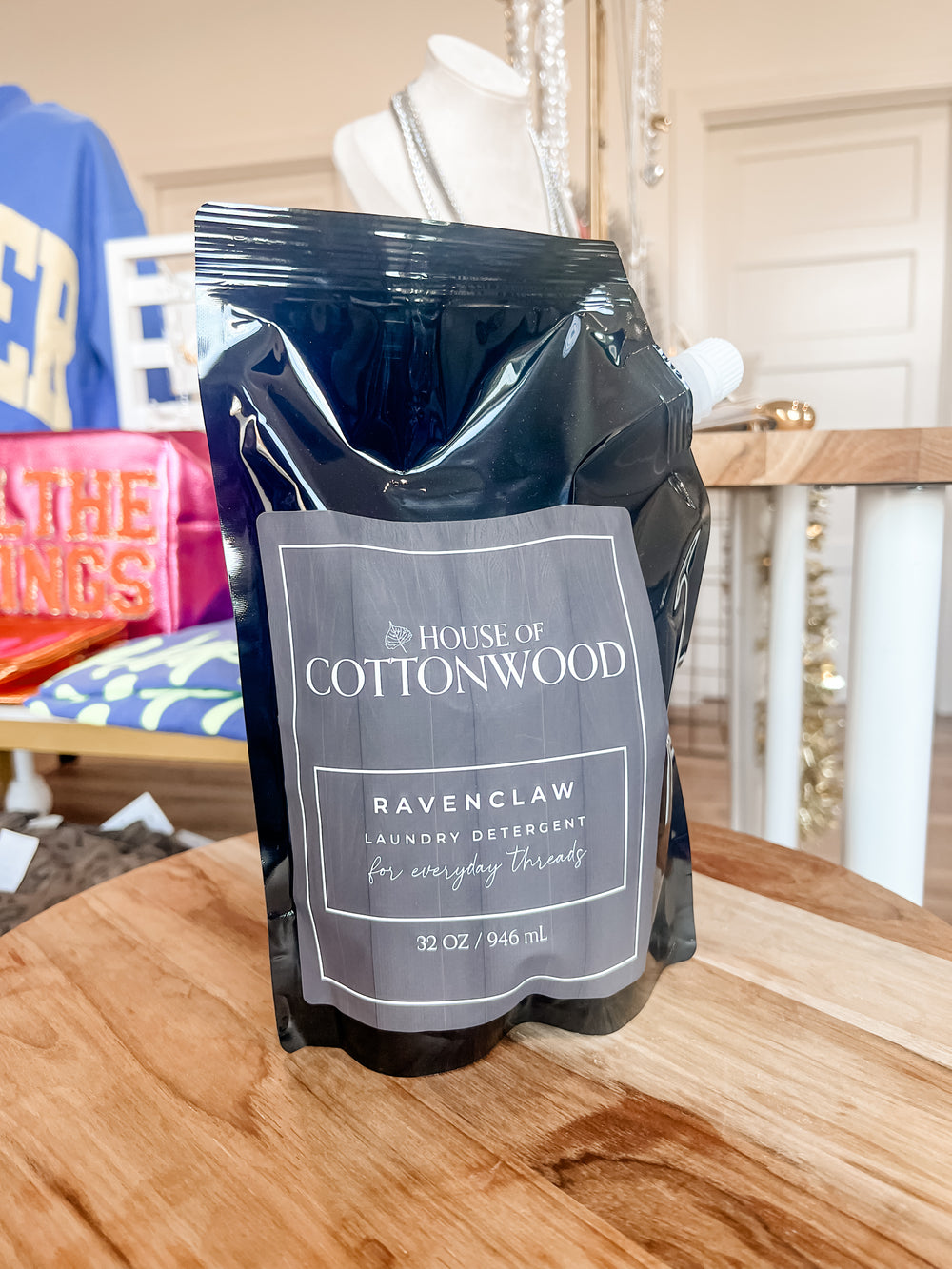 Package of House of Cottonwood laundry detergent on a wooden surface with a blurred background