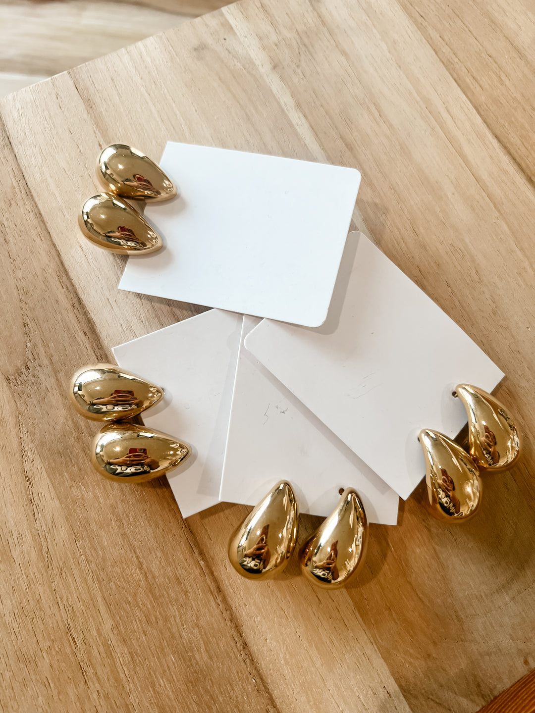 Gold teardrop shaped earrings on a table
