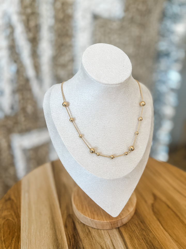 Gold necklace on a white mannequin bust with a blurred background