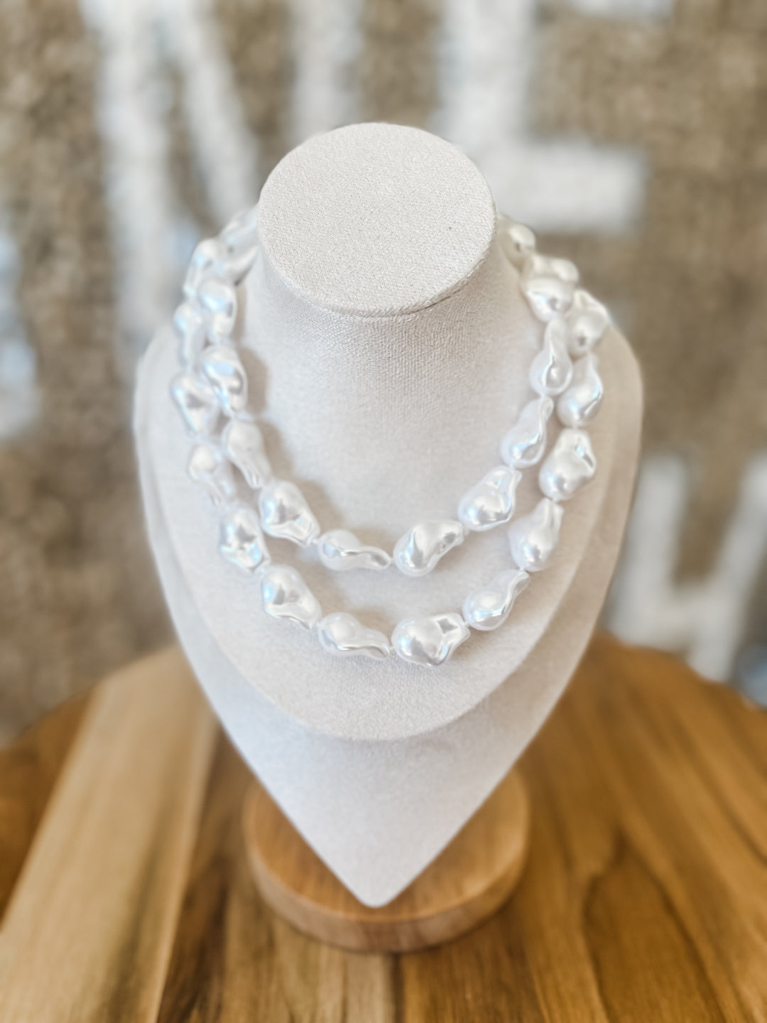 Pearl necklace on a mannequin bust with a neutral background
