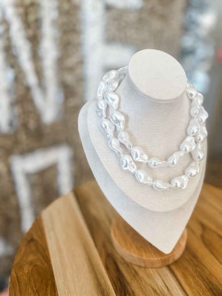 White pearl necklace on a mannequin bust with a blurred background