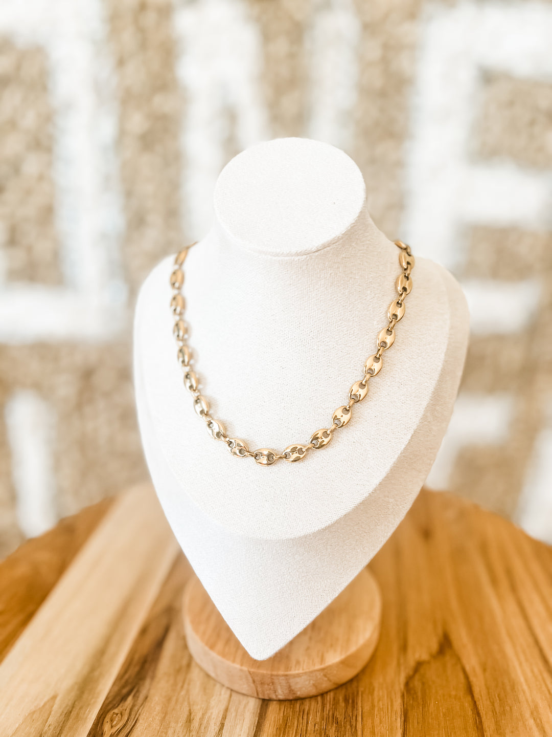 Gold chain necklace on a mannequin bust with a blurred background