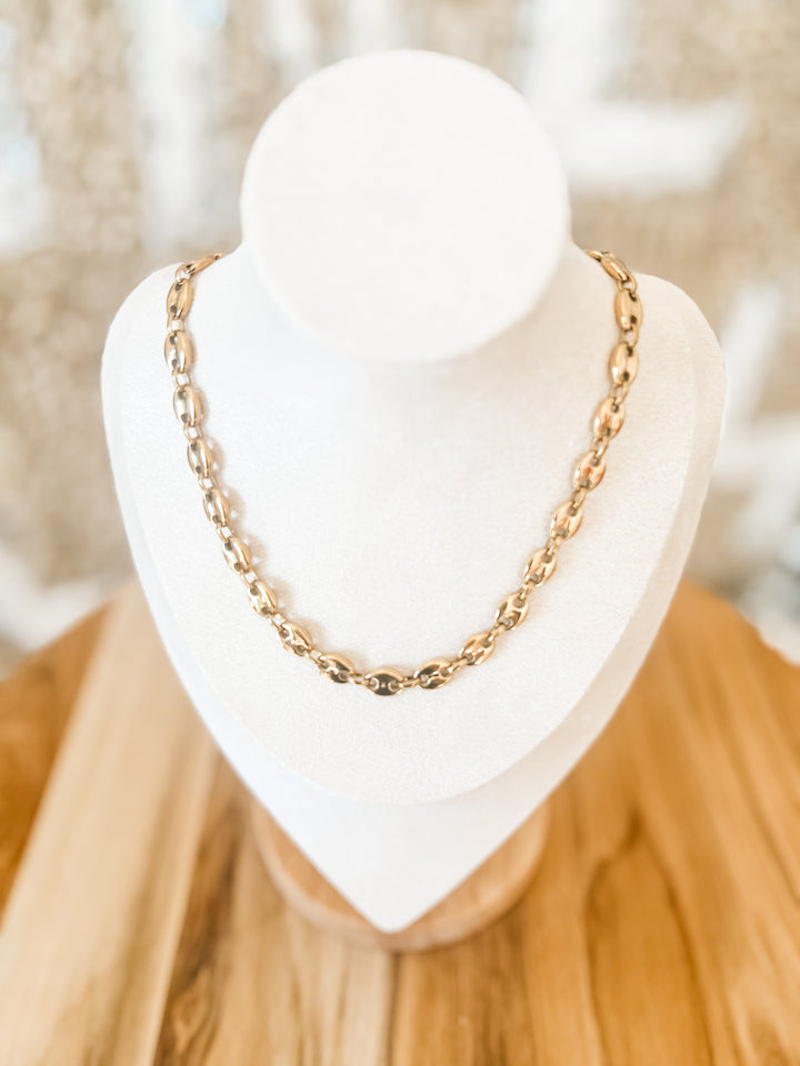 Gold chain necklace on a mannequin bust with a blurred background