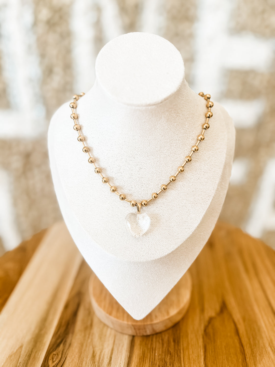 Gold beaded necklace with clear heart pendant