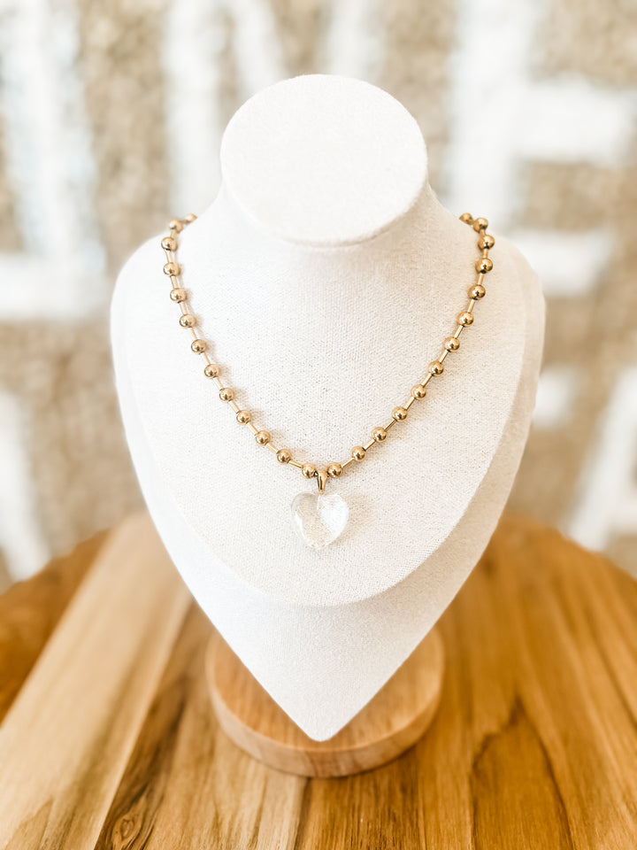 Gold beaded necklace with clear heart pendant