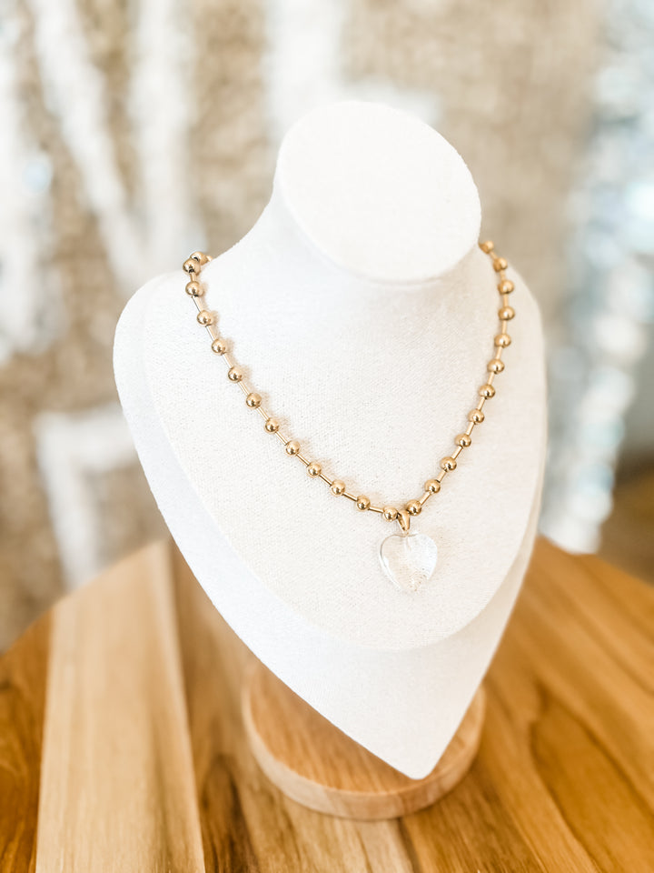 Gold beaded necklace with clear shaped heart pendant
