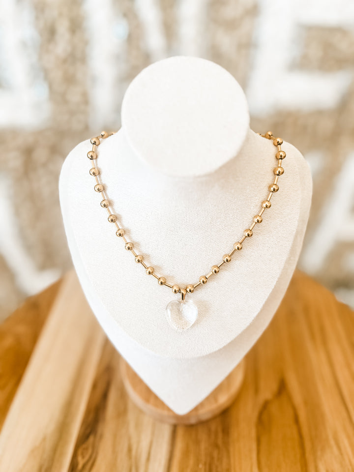Gold beaded necklace with clear heart pendant
