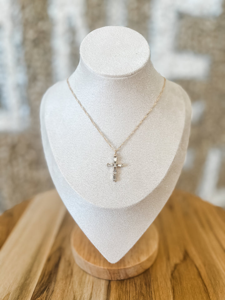 Necklace with a cross pendant on a white bust against a blurred background