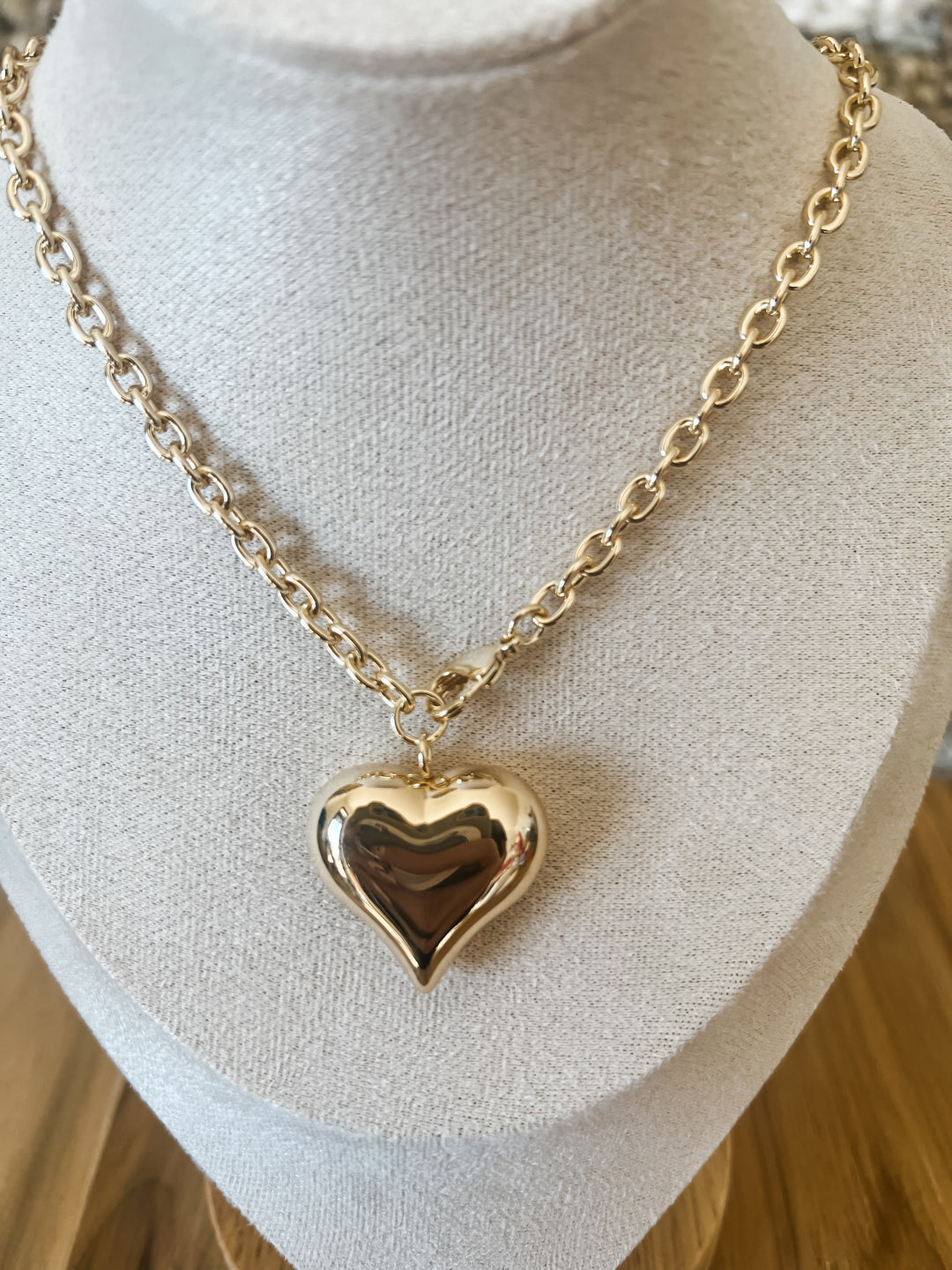 Gold heart-shaped pendant necklace on a mannequin bust.