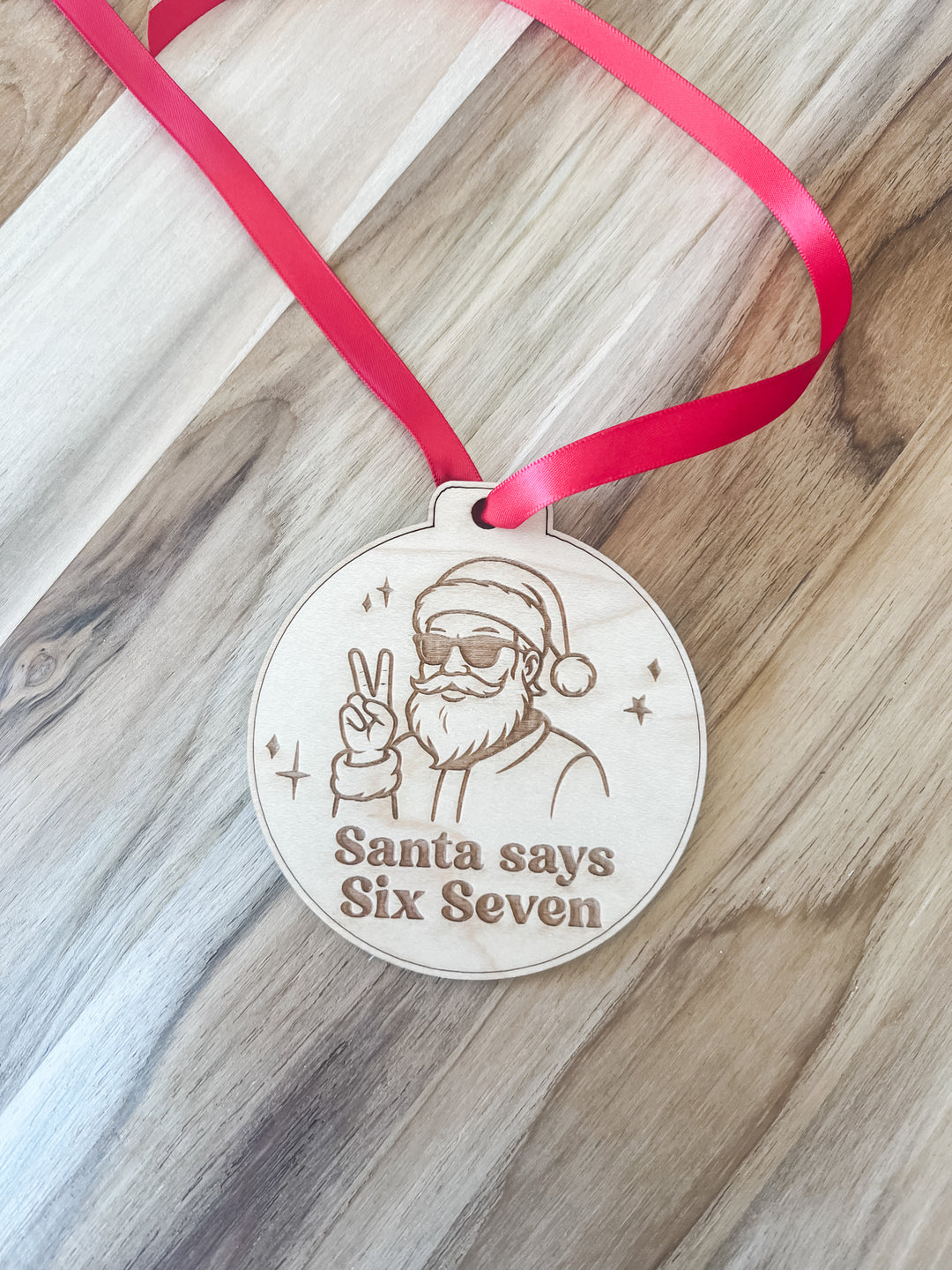 Decorative wooden ornament with Santa Claus design and 'Santa says Six Seven' text