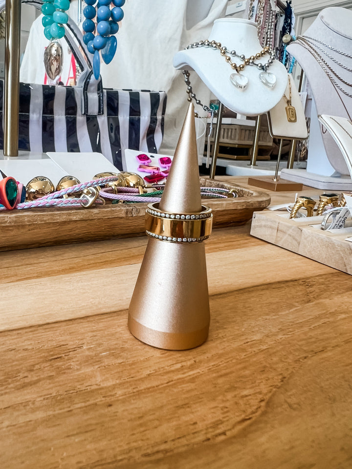 Gold waterproof ring with crystal accents displayed on gold cone ring holder in boutique setting

