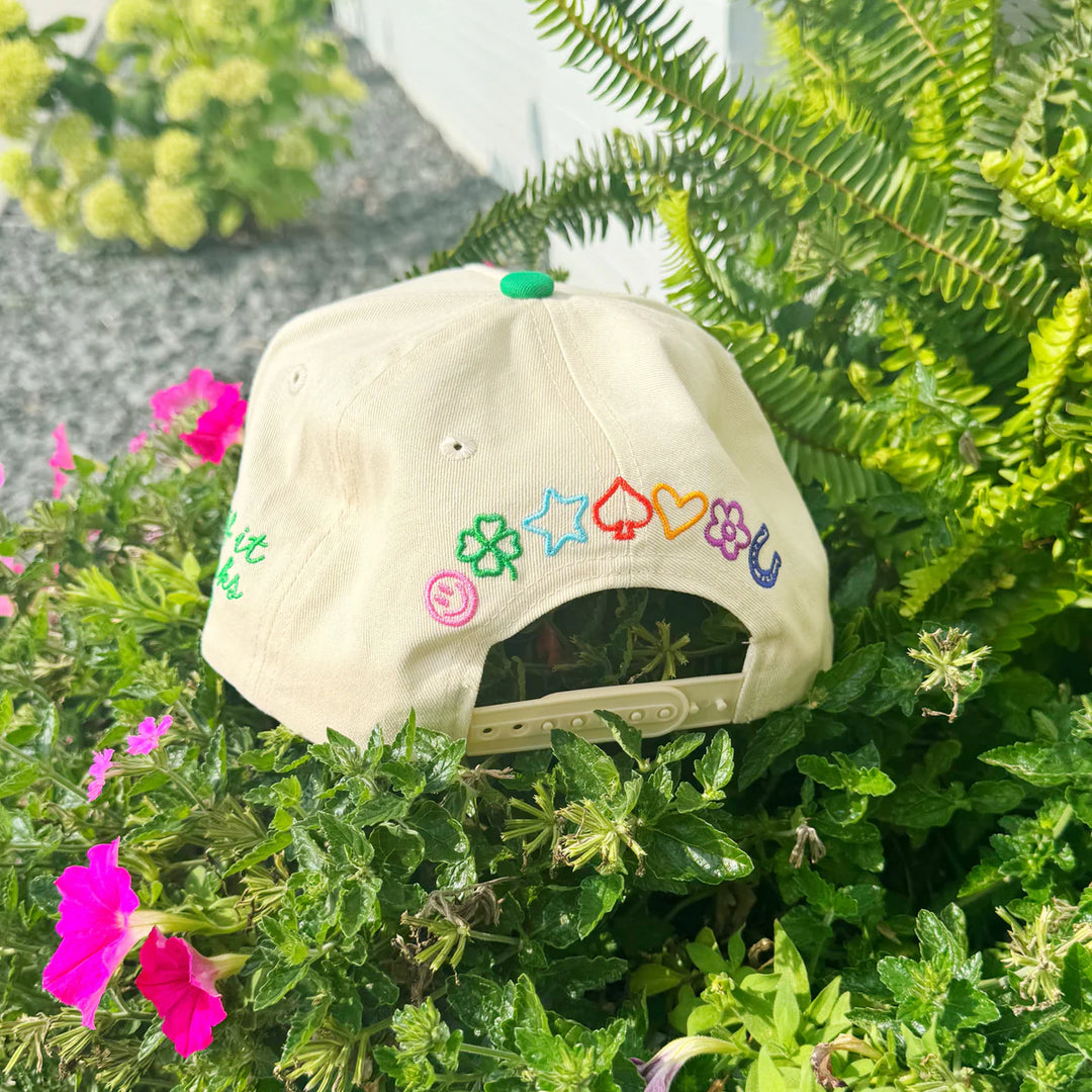 Beige cap with colorful symbols on a green plant background
