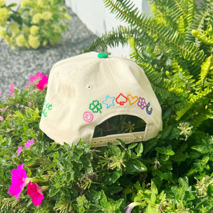 Beige cap with colorful symbols on a green plant background
