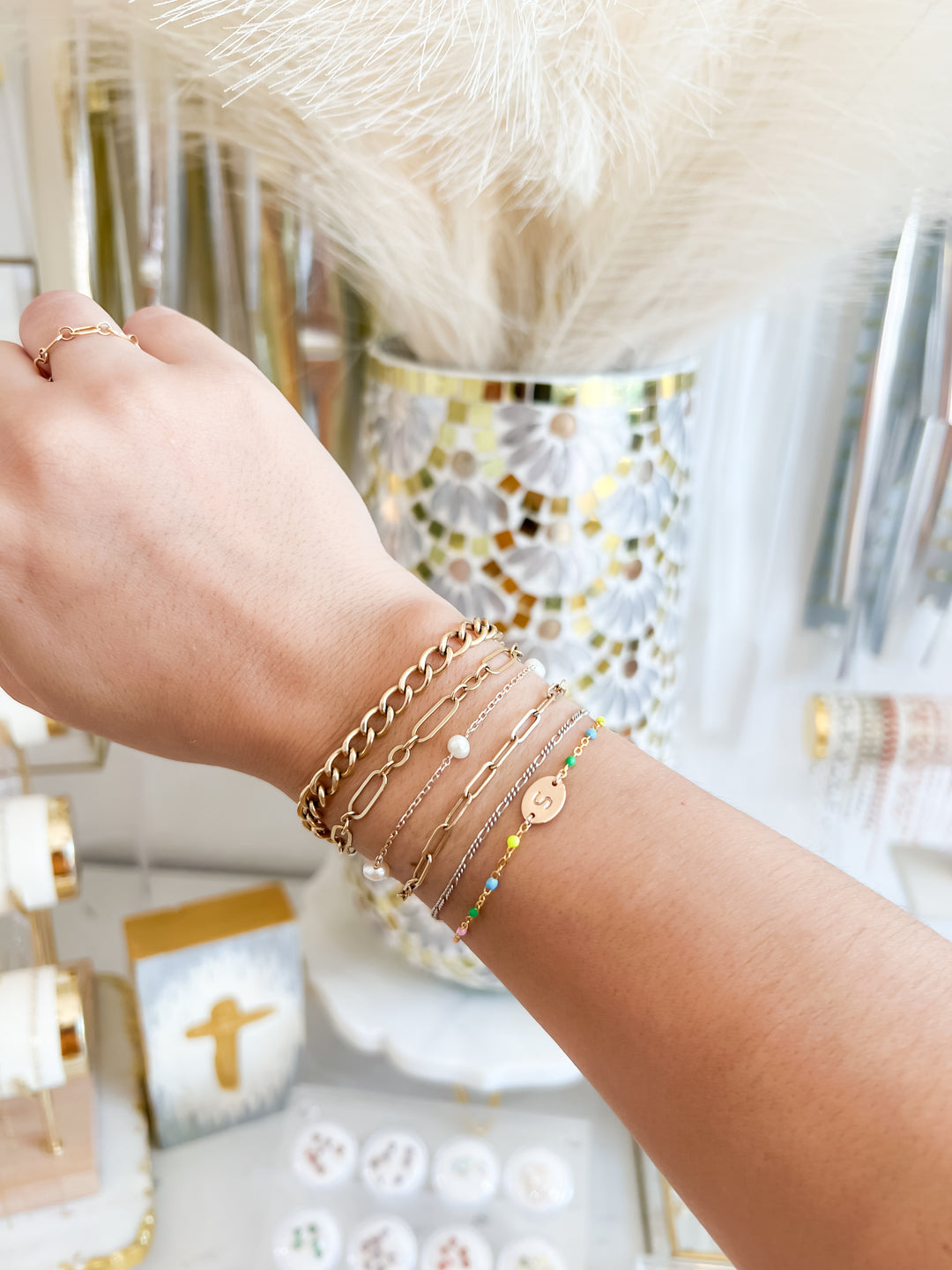 Hand wearing multiple permanent jewelry bracelets