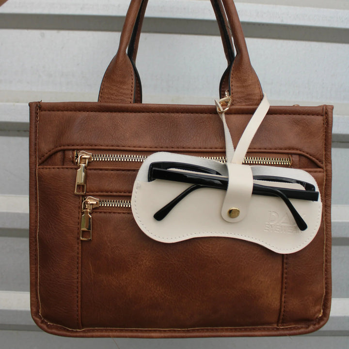 Brown leather handbag with a white sunglasses  pouch holding  sunglasses