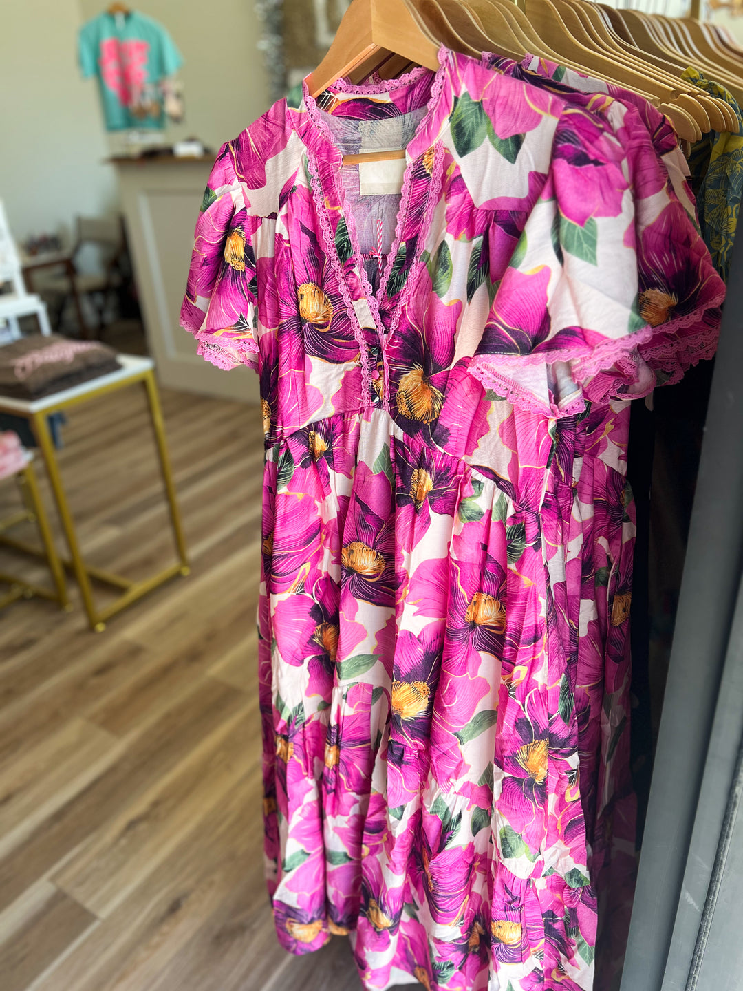 Floral dress with pink and purple colors hanging on a rack.