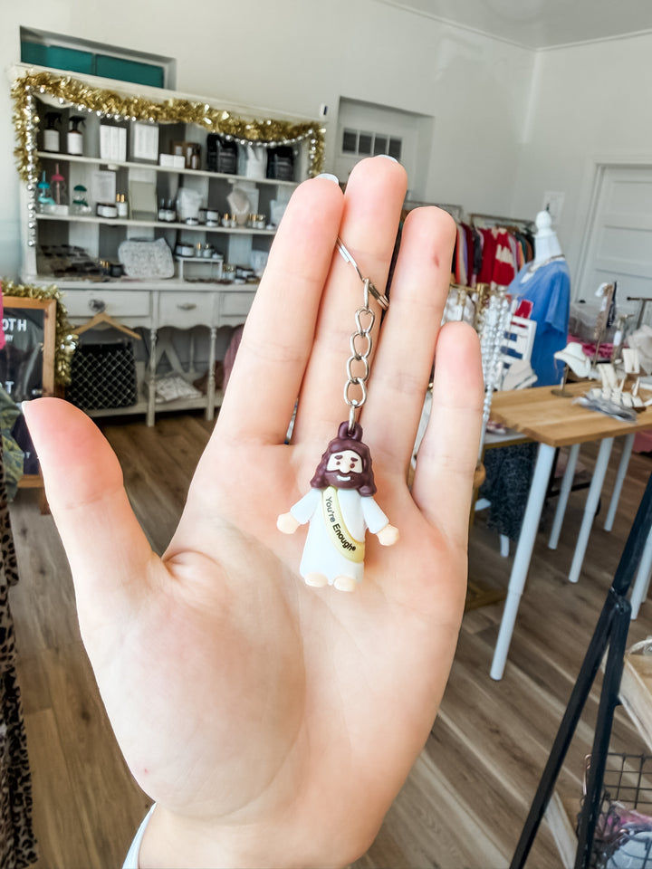 Hand holding a Jesus keychain in a boutique with a blurred background 
