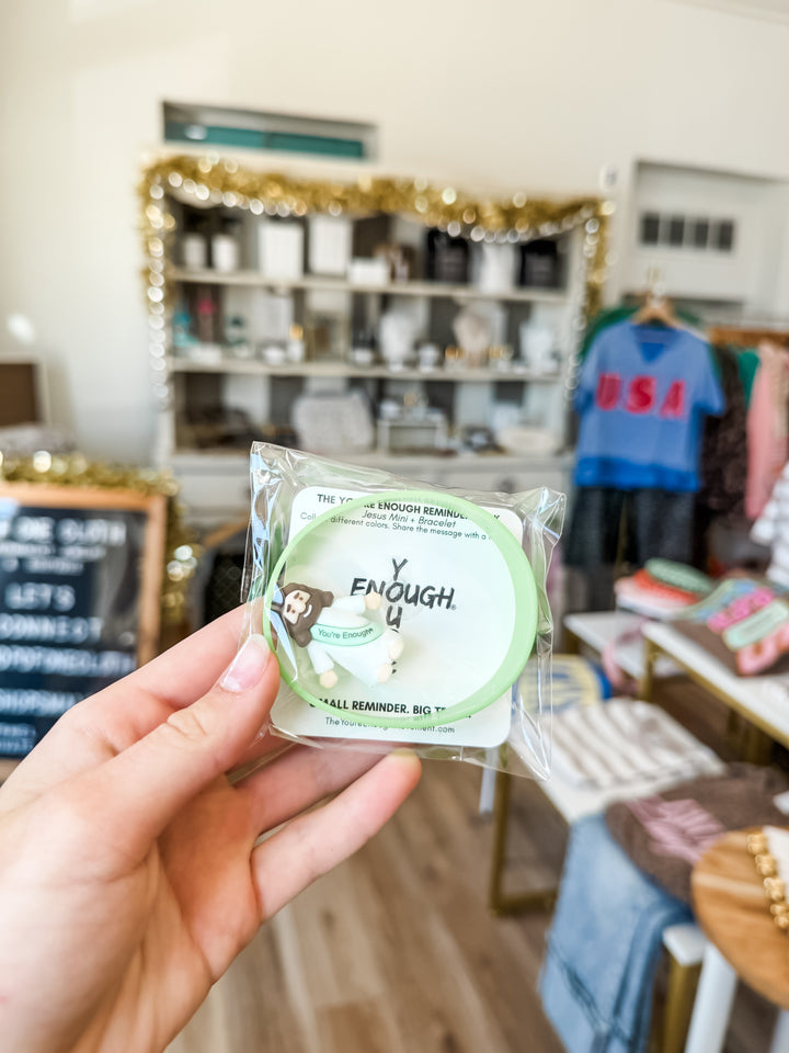 Hand holding the mini Jesus and bracelet combo pack inside boutique 