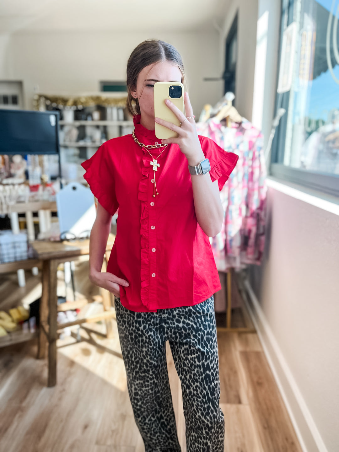 Women wearing red ruffle sleeve top with cold accent necklace stack and leopard pants 