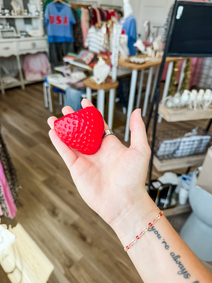 Hand holding a red strawberry squishy fidget toy