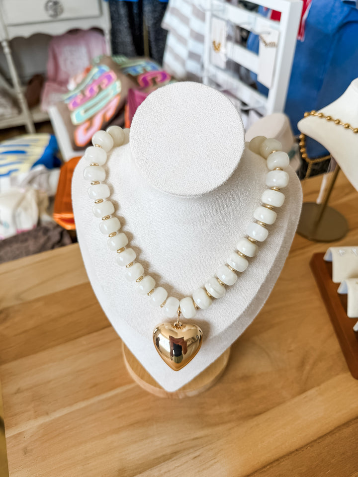 White beaded necklace with gold heart pendant 