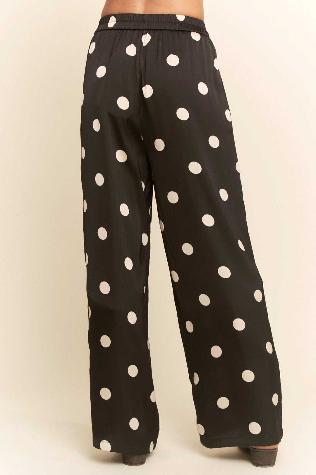 Black pants with white polka dots on a beige background