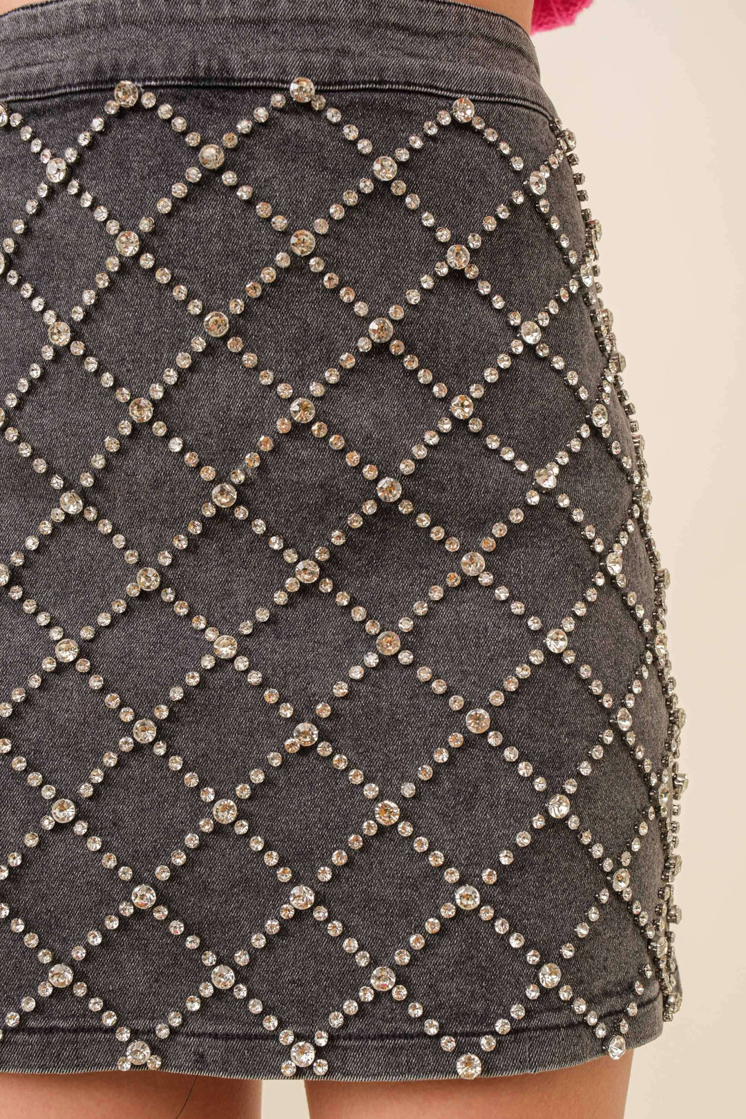 Close-up of a gray skirt with diamond patterned embellishments on a plain background