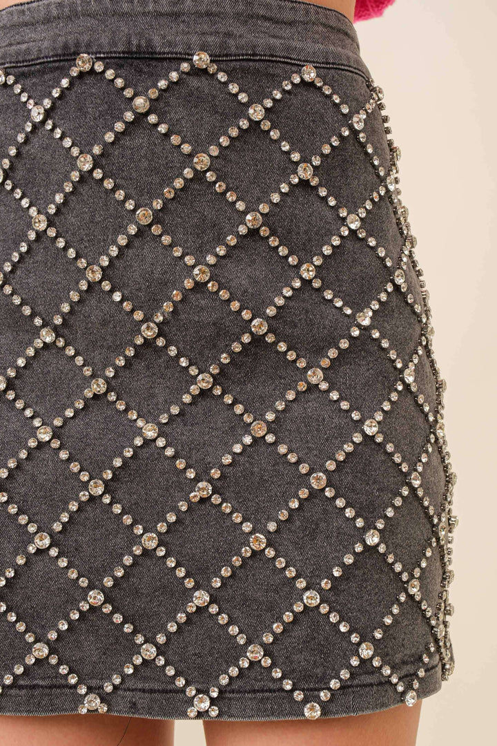 Close-up of a gray skirt with diamond patterned embellishments on a plain background